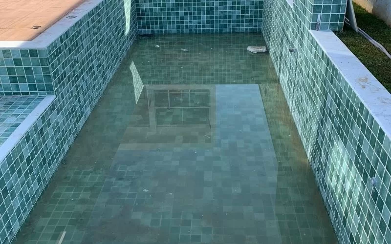 Piscina vazia com azulejos verdes.