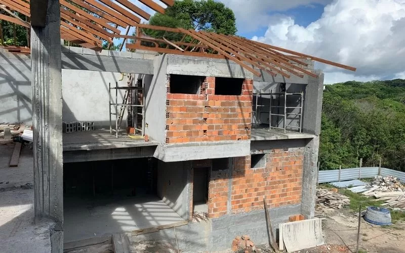 Casa em construção com estrutura de betão e tijolos.