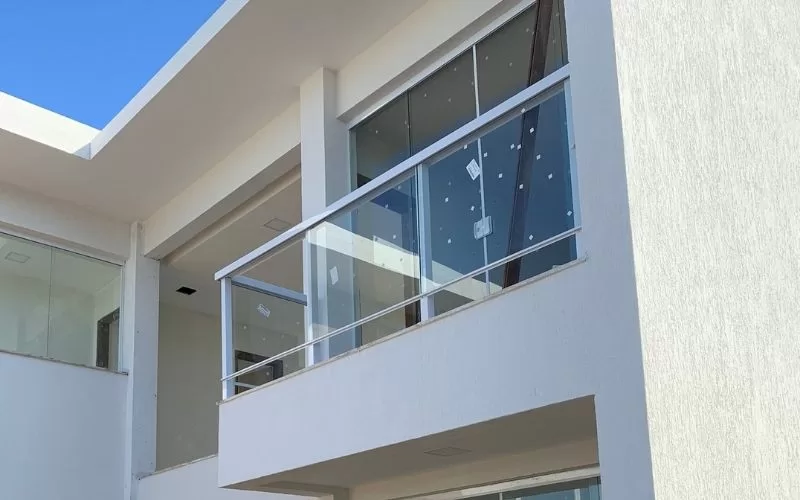 Fachada moderna de prédio com varanda de vidro.
