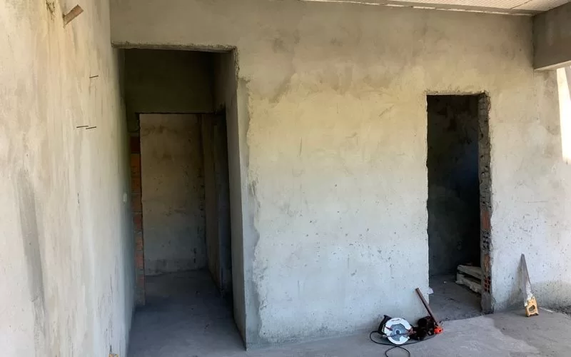 Parede inacabada com portas e ferramentas.