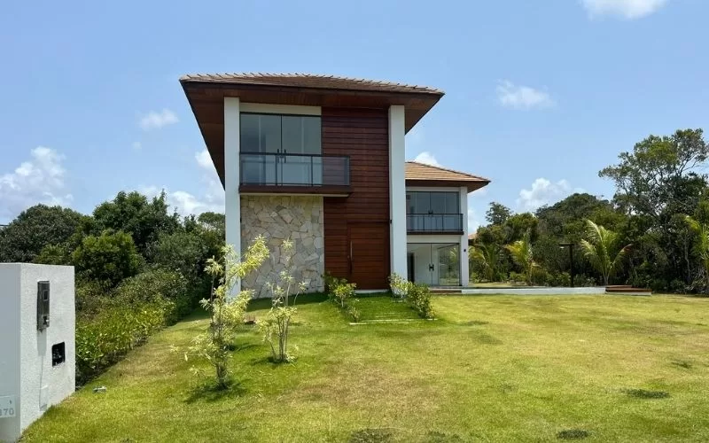 Casa moderna com jardim verde e céu azul.