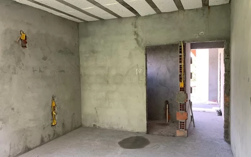 Quarto em construção com paredes rebocadas.