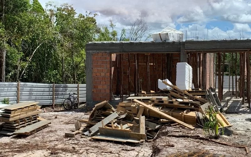 Construção inacabada com materiais empilhados no terreno.