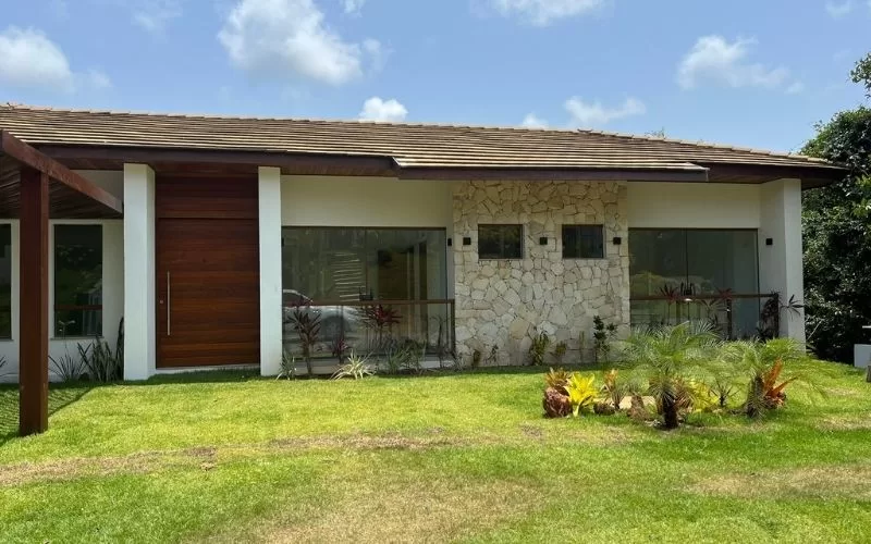 Casa moderna com jardim verde e fachada de pedra.