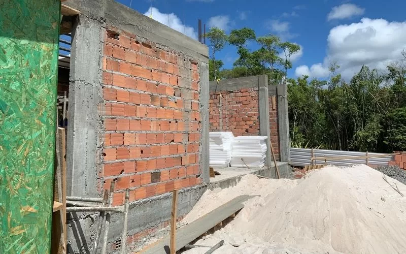 Construção de casa em andamento com tijolos expostos.