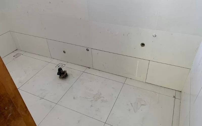 Casa de banho em construção com azulejos brancos.