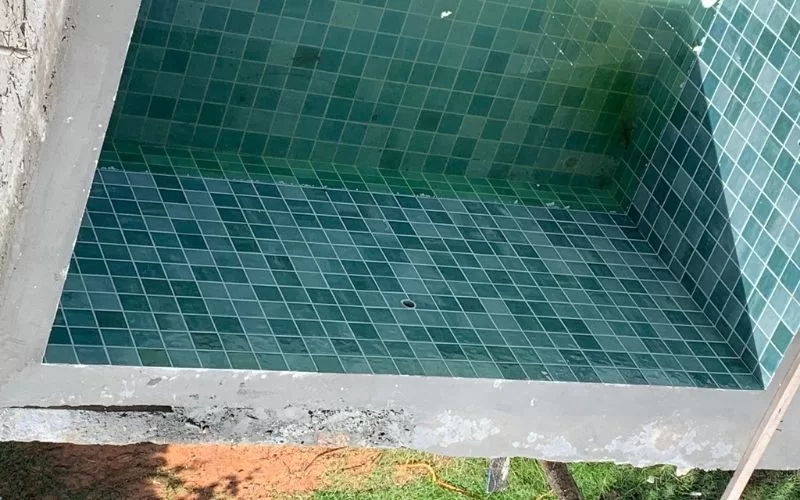 Piscina vazia com azulejos verdes.
