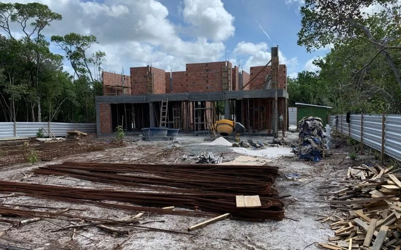 Construção de edifício em andamento com materiais no solo.