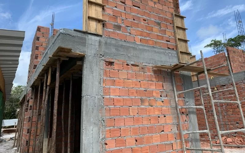 Construção em andamento com tijolos e andaime metálico.