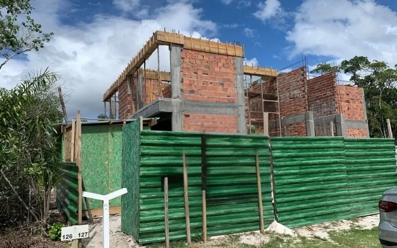 Construção de prédio residencial inacabado com tapume verde.
