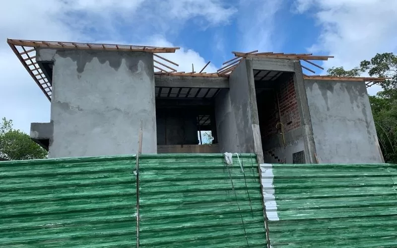 Construção de casa em fase inicial, céu parcialmente nublado.