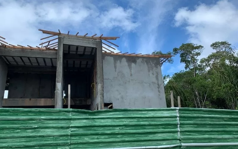 Construção de casa perto de árvores e céu azul.