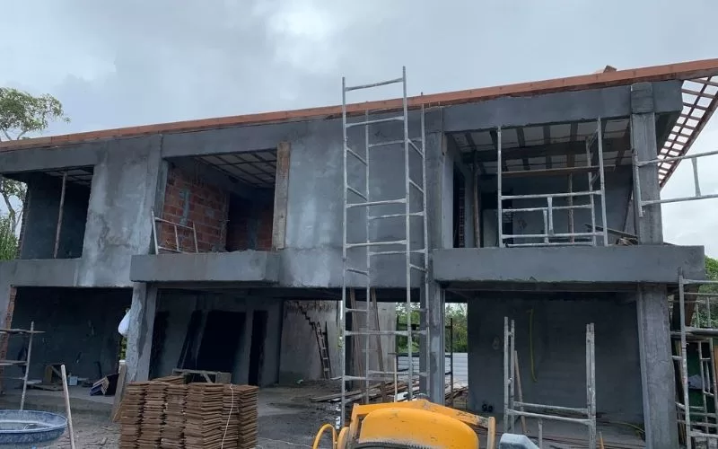 Casa em construção com andaimes e escadas.