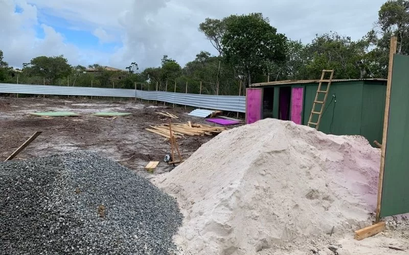 Construção com areia e cascalho em terreno baldio.