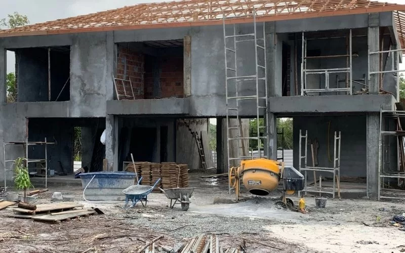 Casa em construção com andaimes e betoneira.