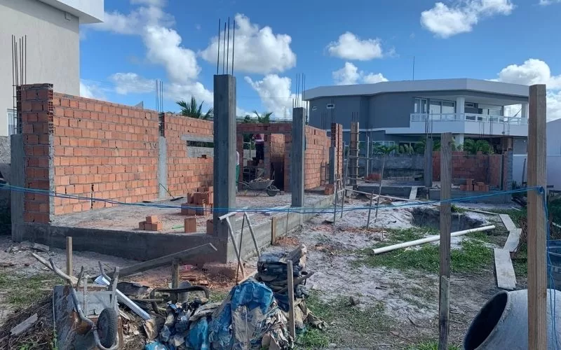 Construção de casa em andamento com tijolos e cimento.