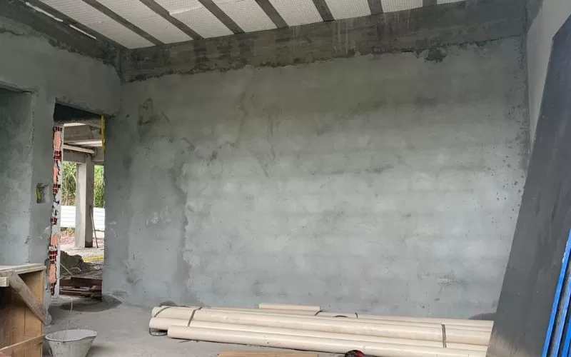 Sala em construção com paredes rebocadas.